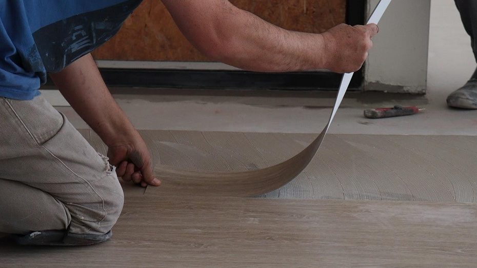 Homem agachado instalando piso vinílico no apartamento